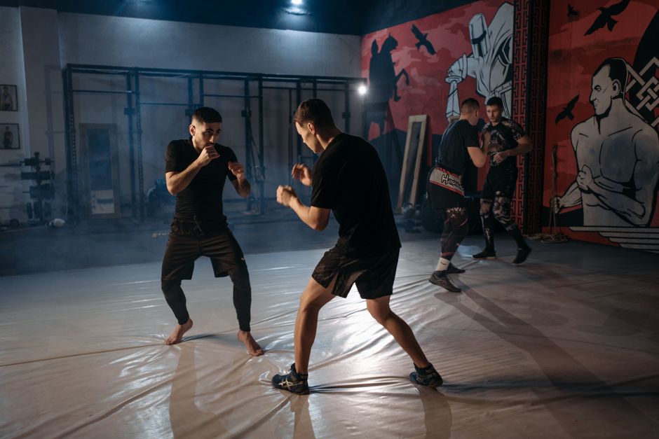 Two martial artists sparring in a gym, one showing focused concentration